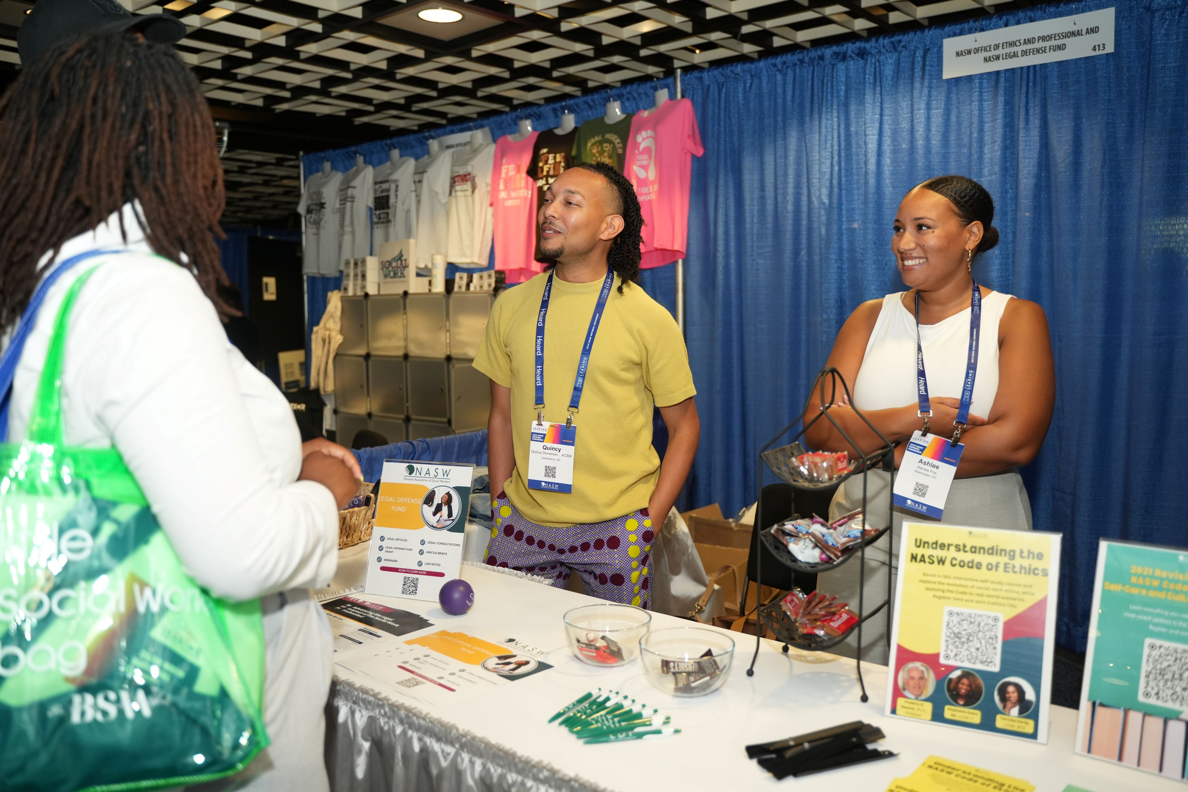 Two persons at a booth speaking with a conference attendee