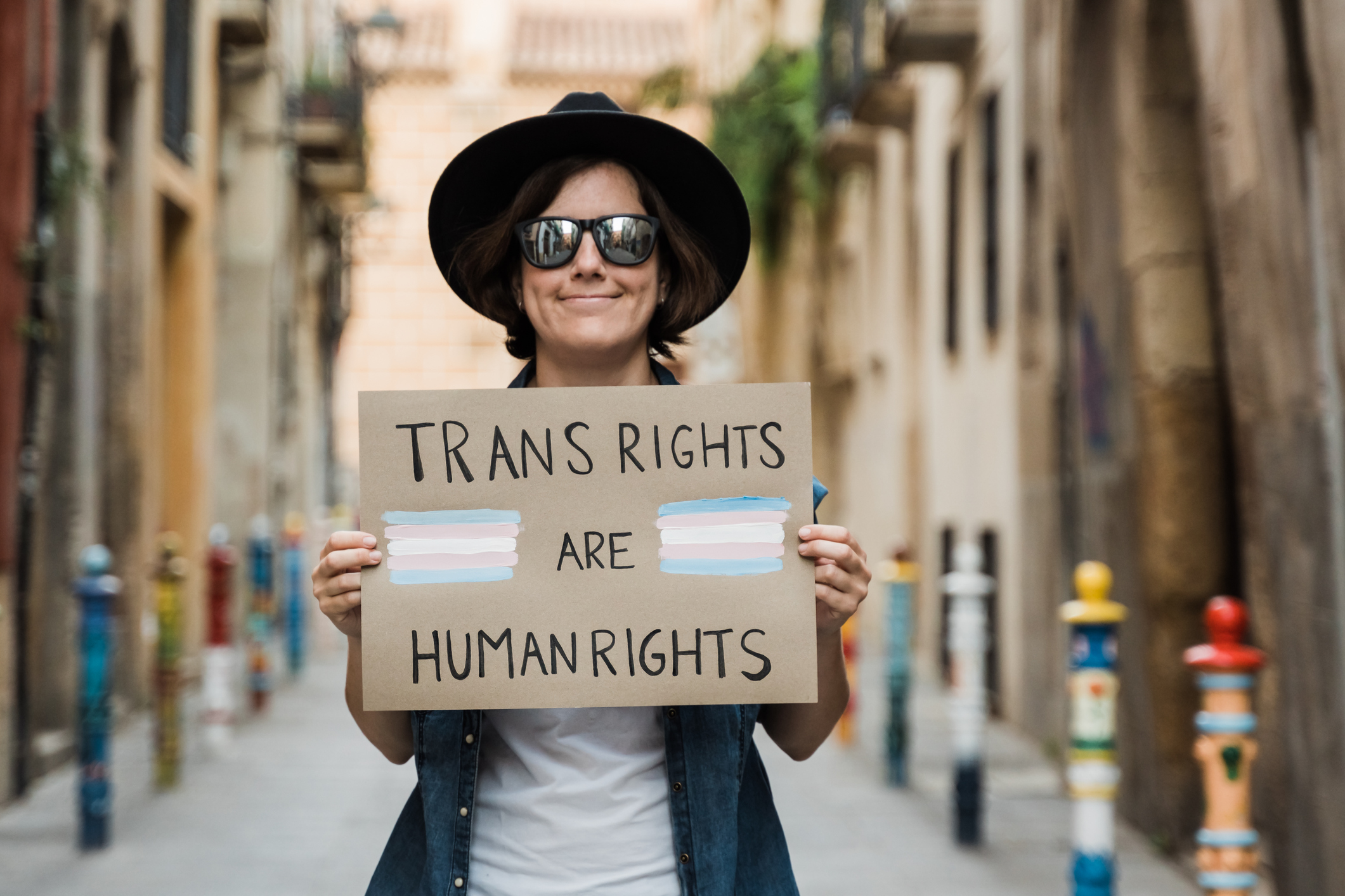 person in hat holding sign saying trans rights are human rights