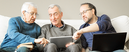 senior man showing media to friends on tablet
